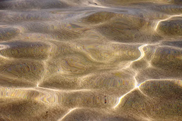 Primo piano Struttura distorta della sabbia sott'acqua. Ondate d'acqua trasparenti, onde di sabbia e bagliore di luce solare. Fondo marino — Foto Stock