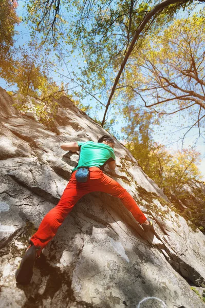 Dorosły brodaty mężczyzna w tym wieku ćwiczy wspinaczkę na skałę w lesie w słoneczny dzień. — Zdjęcie stockowe
