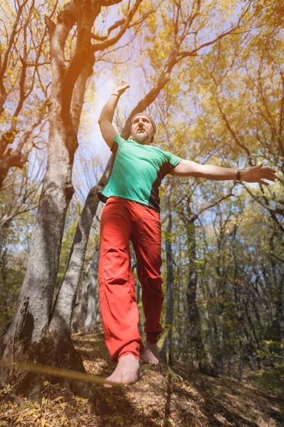 Un hombre barbudo adulto balanceándose en una cuerda floja apretada se dedica a equilibrar el acto en el bosque de otoño — Foto de Stock
