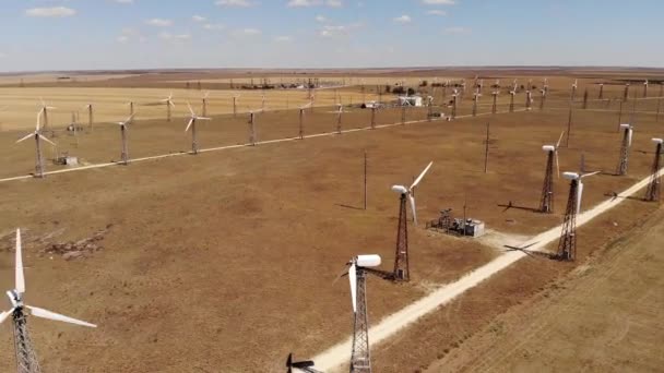 Letecký pohled na větrné turbíny vytvářející čistou větrnou energii mezi žlutými poli. Výroba obnovitelné energie ve stepních oblastech poháněných větrem. — Stock video