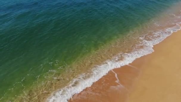 4K vista aérea da praia de areia dourada e ondas espumosas em um dia ensolarado. A melhor ilustração de umas férias à beira-mar ou oceânicas — Vídeo de Stock