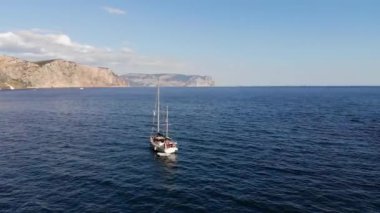 Gündüz gözüyle panoramik manzaralı, suda yüzen yatın dağlarla çevrili olduğu. Döndürme etkisi.