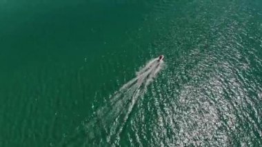 Güneşli bir günde turkuaz açık denizde yüzen bir motorlu teknenin hava görüntüsü. Deniz turizmi ve tekne gezileri.
