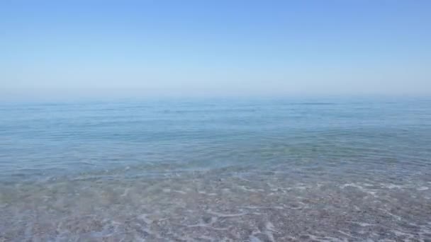 Sebuah pantai sepi di pagi hari dengan nada biru, gelombang kecil berguling di atas pantai berpasir. Kabut di atas laut — Stok Video