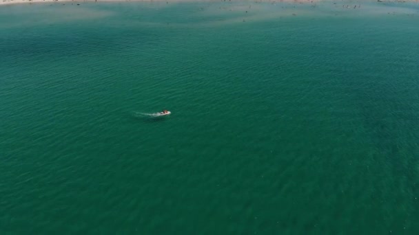 Güneşli bir günde turkuaz açık denizde yüzen bir motorlu teknenin hava görüntüsü. Deniz turizmi ve tekne gezileri. — Stok video