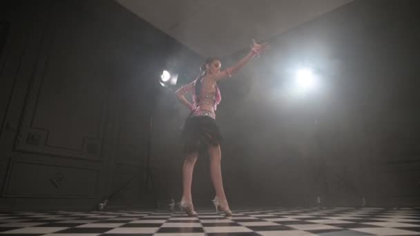 Aantrekkelijke tiener meisje dansen solo ballroom sport dansen latino in een donkere studio kamer gevuld met rook. Professionele danssport — Stockvideo