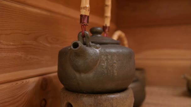 Yixing klei theepot voor een handgemaakte theeceremonie naast ander aardewerk op een houten plank in de kamer — Stockvideo