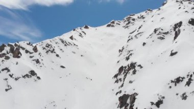 Hava manzaralı. Bir grup kayakçı ve snowboardcu, yüksek dağlarda, karlı Couloir boyunca dik bir iniş için hazırlanıyorlar. Profesyonel kayak sporu..