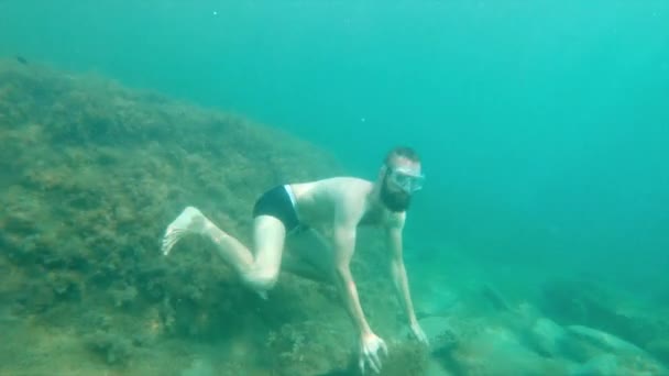 Seorang pria berjanggut tanpa peralatan bawah air pura-pura bermeditasi di laut. Gerakan lambat — Stok Video