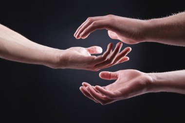 İki el birbirini tutuyor. Şefkat, ilgi ve desteğin sembolü. Karanlık bir arka planda bir kadının erkeği.