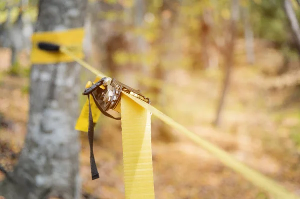 Ο εξοπλισμός παραπλάνησης δίπλα στο μηχάνημα. τεντωμένο κίτρινο σχοινί στο δάσος του φθινοπώρου — Φωτογραφία Αρχείου