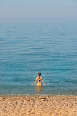Mayolu çekici genç bir kadın, sakin sabah suyunun içinde belime kadar duruyor.