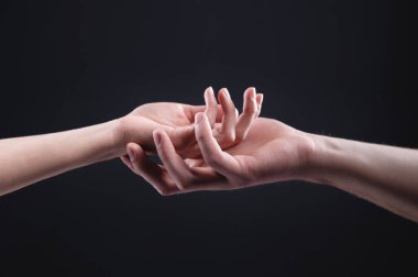 İki el birbirini tutuyor. Şefkat, ilgi ve desteğin sembolü. Karanlık bir arka planda bir kadının erkeği.
