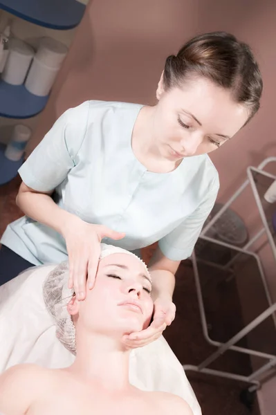 Masajista profesional mujer haciendo masaje facial al cliente en el salón de spa — Foto de Stock