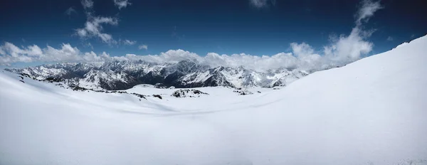 Panorama alpino da Grande Cordilheira do Cáucaso coberta de neve em um dia ensolarado com cobertura variável de nuvens. Declives panorâmicos ideais para esqui, freeriding, esqui e snowboard — Fotografia de Stock