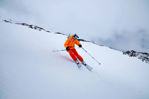 Um esquiador profissional na velocidade estabelece-se em uma curva. Esqui no inverno em um dia nublado — Fotografia de Stock