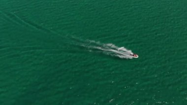 Güneşli bir günde turkuaz açık denizde yüzen bir motorlu teknenin hava görüntüsü. Deniz turizmi ve tekne gezileri.