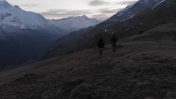 Vista aérea de un hombre y una mujer caminando en lo alto de las montañas y admirando la vista. Senderismo deportivo de montaña — Vídeos de Stock