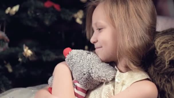 Uma menina sorridente em um vestido rosa solitário olha para seu brinquedo de pelúcia. Férias estragadas. Uma criança invejosa — Vídeo de Stock