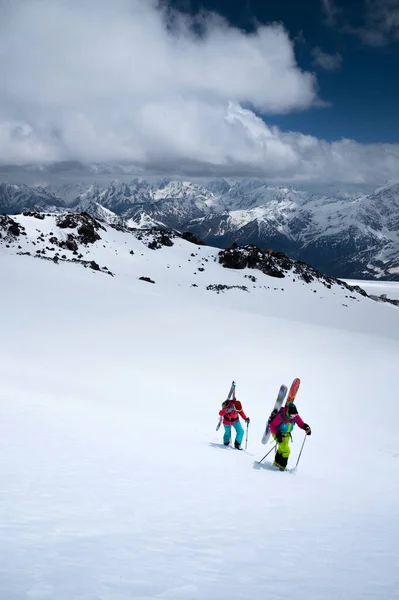 Duas mulheres jovens esportistas backcountry escalando na neve no alto das montanhas para freeride esqui fora de pistas — Fotografia de Stock