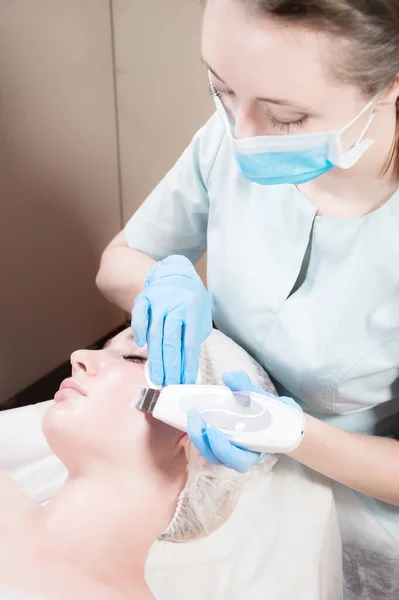 Una donna caucasica alla reception dell'estetista fa una procedura di pulizia del viso ad ultrasuoni. Cosmetologia — Foto Stock