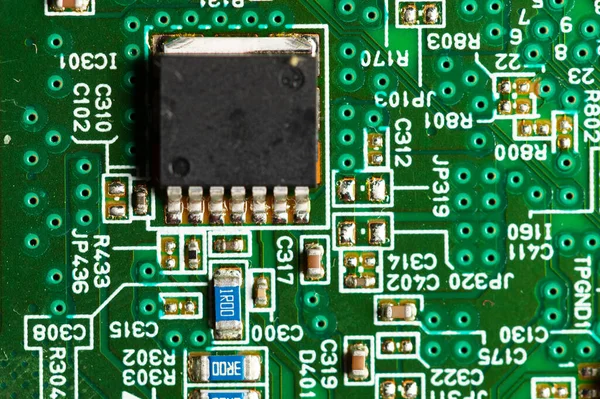 Microchip de primer plano de circuito electrónico en un microcircuito verde con elementos de transistores y flejes —  Fotos de Stock