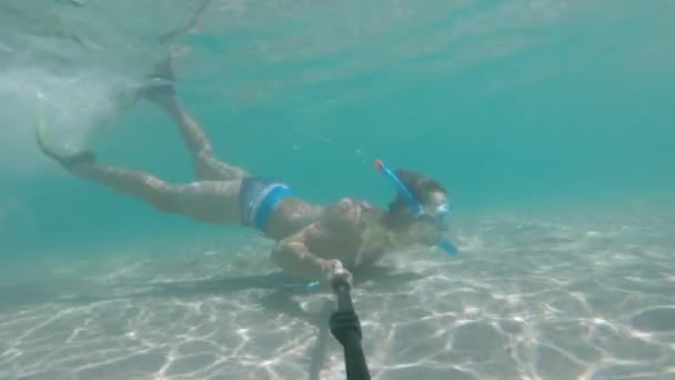 Ein sportlicher junger Mann in Maske und Schnorchel mit Flossen schwimmt unter Wasser. — Stockvideo