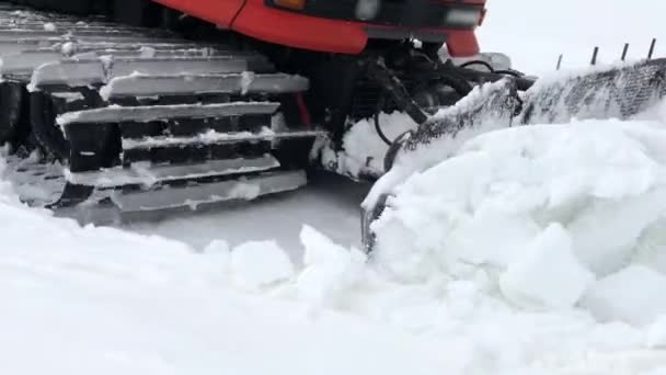 Primer plano del trabajo de los paseos de snowcat ancho en la nieve y rastrillos contra el telón de fondo de las montañas cubiertas de nieve. concepto de preparación de pistas de nieve para la temporada de esquí y la cosecha de nieve — Vídeo de stock