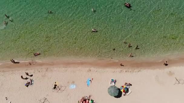 Aerial view of azure beach of central asia with tourists resting and beach umbrellas top view. Background for tourism and recreation by the sea — Stock Video