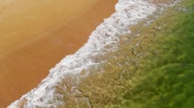 Okyanus mavi dalgalarının kumsala çarptığını gösteren hava manzarası. Deniz dalgaları ve kumlu kumsalın güzel havadan çekilmiş görüntüsü..