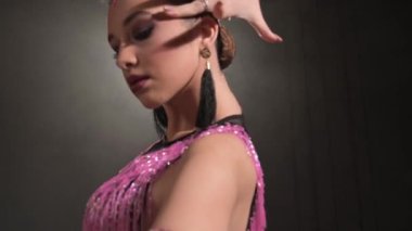 Karanlık bir odada gösterişsiz bir odada Latin dansı yapan çekici bir genç kız. Profesyonel balo salonu sporları dans 4K