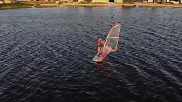 Bir rüzgar sörfü tahtası uçurmayı öğrenen genç bir kadının havadan görünüşü. Gün batımı egzersizi. Alçak tuş — Stok video