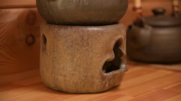 Yixing klei theepot voor een handgemaakte theeceremonie naast ander aardewerk op een houten plank in de kamer — Stockvideo