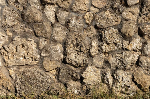 A fachada exterior do edifício é feita de pedra natural de várias formas. Textura de fundo para decoração ao ar livre sob a Idade Média — Fotografia de Stock