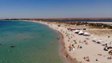 Orta Asya 'nın gökyüzü manzarası, dinlenen turistler ve plaj şemsiyeleri. Deniz kenarında turizm ve eğlence için arka plan