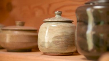 Kil çaydanlığı, el yapımı çay seremonisi için diğer toprak malzemelerinin yanında, odasındaki ahşap bir rafta.