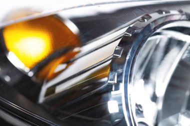 Makro yakın çekim faktörü, farı fıskiyedeki yeni farın yansıtıcısı. Yumuşak odaklı araba arkaplanı