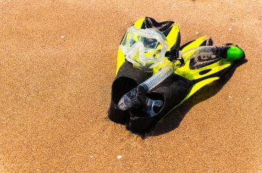 Şnorkelle yüzme ekipmanları deniz kıyısında altın kumun üzerinde yüzgeçlerini yerleştirdi.