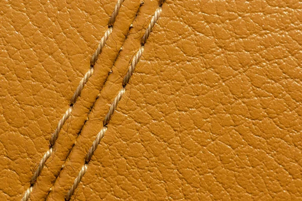 Close-up of beige orange faux leather stitching in the car interior. Background for interior trim comfort — Stock Photo, Image