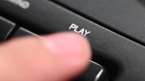 Close-up profundidade rasa de campo. Um dedo de homem pressiona um botão para jogar em um gravador antigo. Comece a tocar uma música — Vídeo de Stock