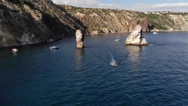 Vista aérea de barcos turísticos en la bahía de mar junto a rocas individuales y alta costa rocosa. Vacaciones mediterráneas de lujo — Vídeo de stock