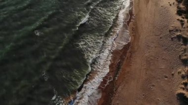 Uçuşun dik kayalık kıyı şeridi üzerindeki havadan görüntüsü. Dalgalar ve köpüklerle dolu bir fırtına sırasında deniz.