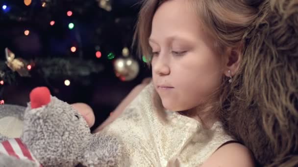 Rok krysy. Šťastný kavkazský dítě dívka poblíž vánočního stromečku objímající krysa. na pozadí blikajících světel vánočního stromku — Stock video