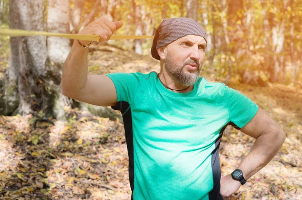 Retrato de um homem barbudo na idade fica perto de um slackline tenso em uma floresta de outono — Fotografia de Stock