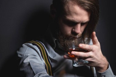 Pantolon askılı şık sakallı adam viski kokusu alıyor. Stüdyo resmi