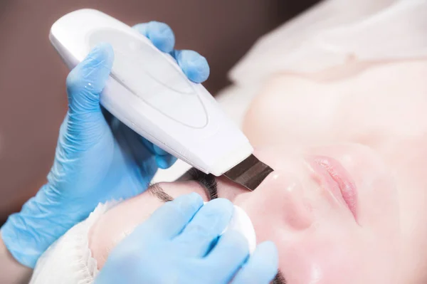 Zbliżenie kaukaska kobieta na recepcji w kosmetyczka robi ultradźwiękowy zabieg czyszczenia twarzy. Kosmetologia — Zdjęcie stockowe