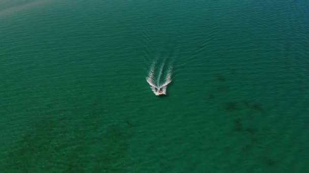 Luchtfoto van een motorboot die op een zonnige dag over de heldere turquoise zee vaart. Zeetoerisme en boottochten op zee — Stockvideo