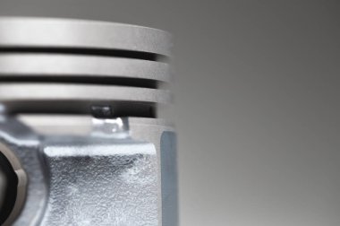 Gri arkaplandaki içten yanmalı motorun yakın çekim pistonu. Motor tamiri için yeni yedek parça. Arkaplanı onar