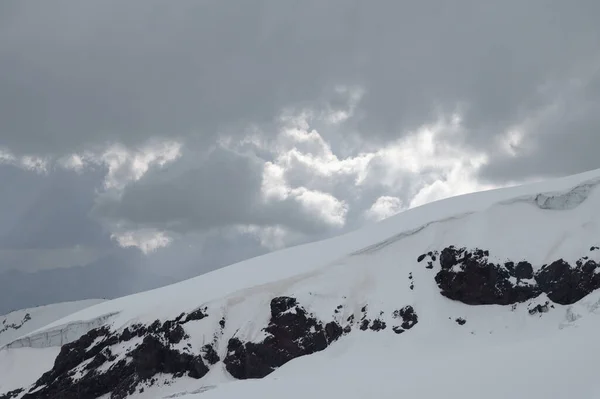 Picos nevados de las altas montañas caucásicas por la noche. Cielo dramático —  Fotos de Stock