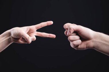 Erkek ve kadın elleri siyah arka planda kağıt makas taşı oynarlar. Çatışmaları barışçıl ve ekolojik bir yolla çözme kavramı